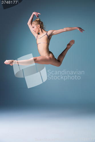 Image of Young beautiful modern style dancer jumping on a studio background