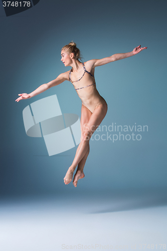 Image of Young beautiful modern style dancer jumping on a studio background