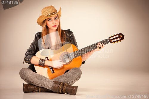 Image of The beautiful girl in a cowboy\'s hat and acoustic guitar.