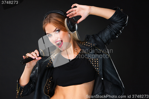 Image of Portrait of a beautiful woman singing into microphone with headphones 