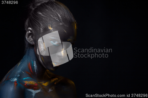 Image of Portrait of a young woman who is posing covered with  black paint 