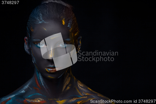 Image of Portrait of a young woman who is posing covered with  black paint 