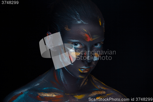 Image of Portrait of a young woman who is posing covered with  black paint 