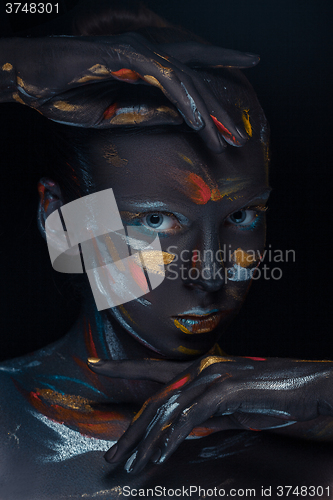 Image of Portrait of a young woman who is posing covered with  black paint 