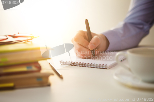 Image of The male hand with a pen and the cup