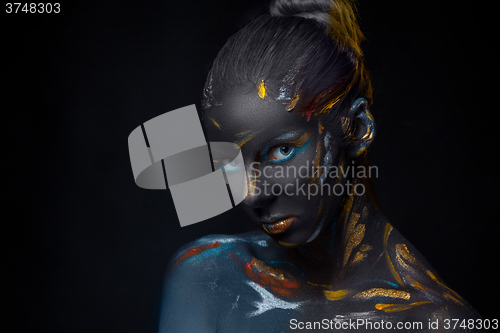 Image of Portrait of a young woman who is posing covered with  black paint 