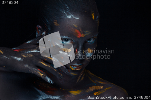 Image of Portrait of a young woman who is posing covered with  black paint 