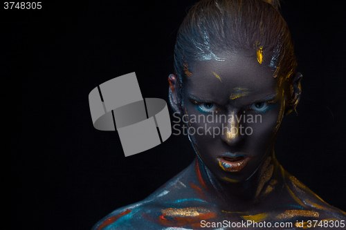 Image of Portrait of a young woman who is posing covered with  black paint 