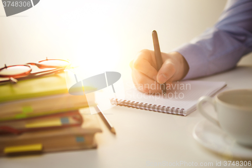 Image of The male hand with a pen and the cup