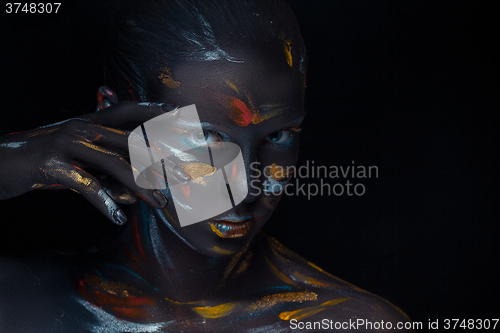 Image of Portrait of a young woman who is posing covered with  black paint 