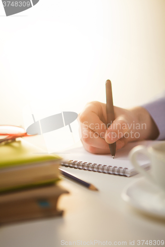 Image of The male hand with a pen and the cup