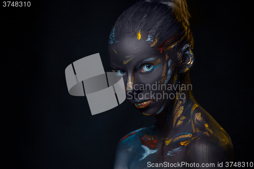 Image of Portrait of a young woman who is posing covered with  black paint 