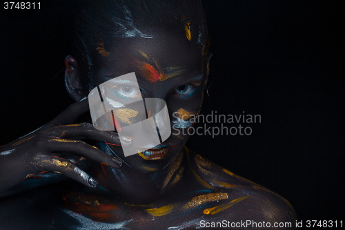 Image of Portrait of a young woman who is posing covered with  black paint 