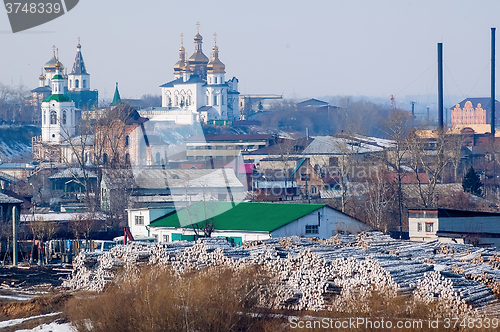 Image of Big pile of logs and two churches. Tyumen. Russia