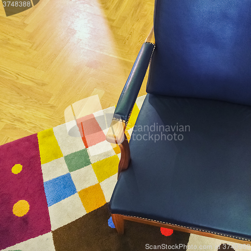 Image of Blue leather armchair on colorful rug