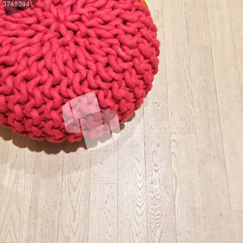 Image of Woven red pouf on wooden floor