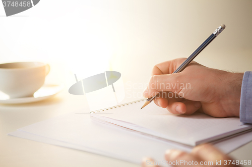 Image of The male hands with a pencil and the cup