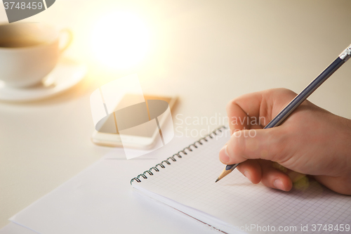 Image of The male hands with a pencil and the cup