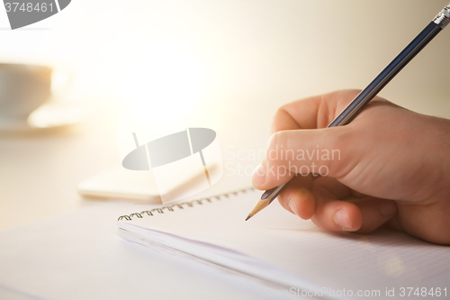 Image of The male hand with a pencil and the cup