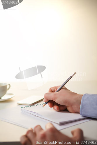 Image of The male hands with a pencil and the cup