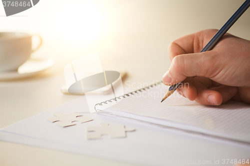 Image of The male hands with a pencil and the cup