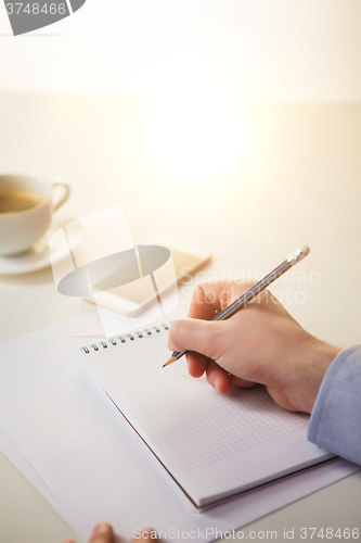 Image of The male hands with a pencil and the cup