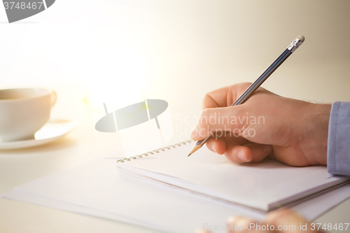 Image of The male hand with a pencil and the cup