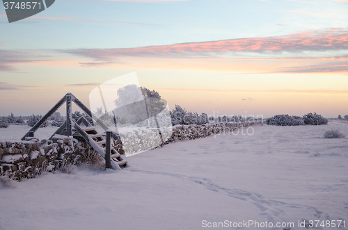 Image of Dawn at a winterland with a stile by stone wall