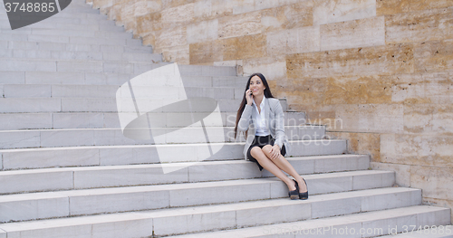 Image of Happy executive with phone and seated on stairs