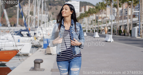 Image of Trendy jaunty young woman enjoying a stroll