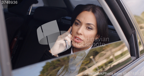 Image of Serious female executive on phone in limousine
