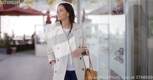 Image of Smiling stylish woman walking past a shop