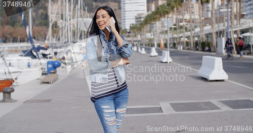 Image of Young woman chatting on her phone in the street