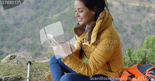 Image of Smiling female hiker using her phone