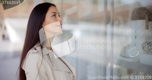 Image of Thoughtful young woman eyeing shop merchandise