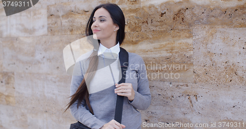 Image of Grinning woman in sweater near wall looking over