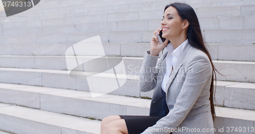 Image of Laughing woman sitting on steps with phone