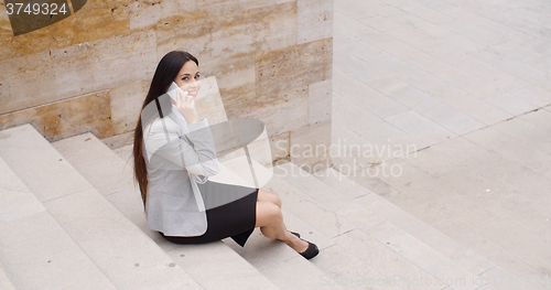 Image of Cute business woman sitting on steps with phone