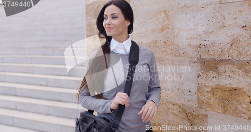 Image of Grinning woman in sweater near wall looking over