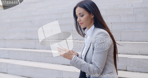 Image of Pretty young worker sitting on steps with phone