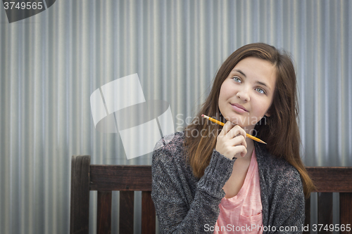 Image of Young Daydreaming Female Student With Pencil Looking to the Side