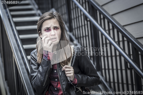 Image of Young Bruised and Frightened Girl With Backpack on Staircase