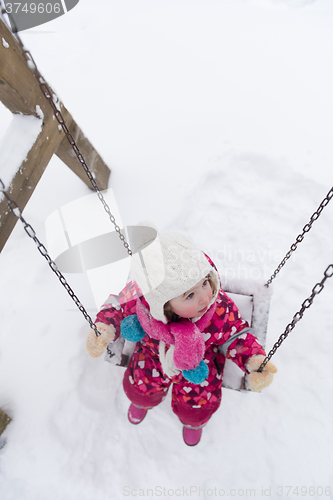 Image of little girl at snowy winter day swing in park