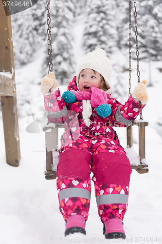 Image of little girl at snowy winter day swing in park