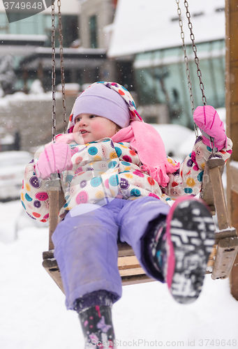 Image of little girl at snowy winter day swing in park