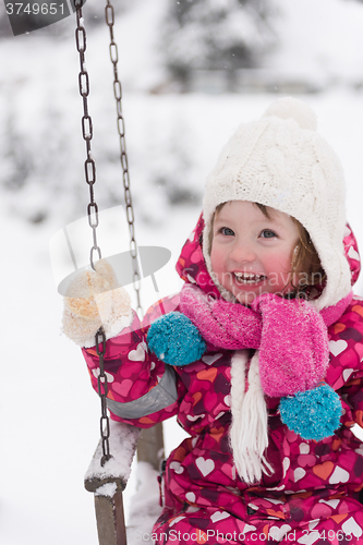 Image of little girl at snowy winter day swing in park