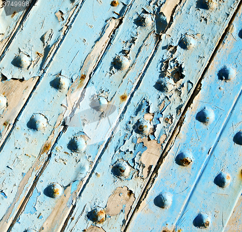 Image of stripped paint in the blue wood door and rusty nail