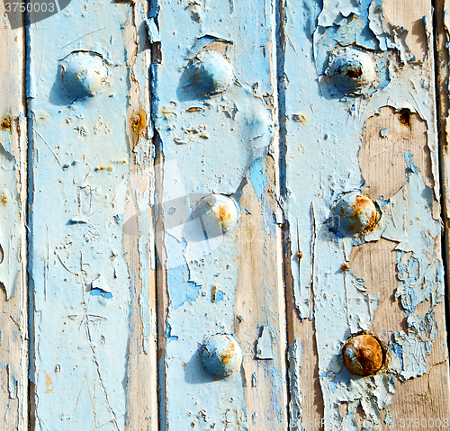 Image of stripped paint in the blue wood door and rusty nail