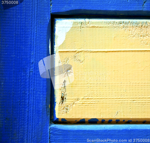 Image of dirty stripped paint in the blue wood door and rusty nail