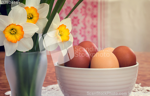 Image of Easter eggs in a ceramic vase and flowers daffodils.